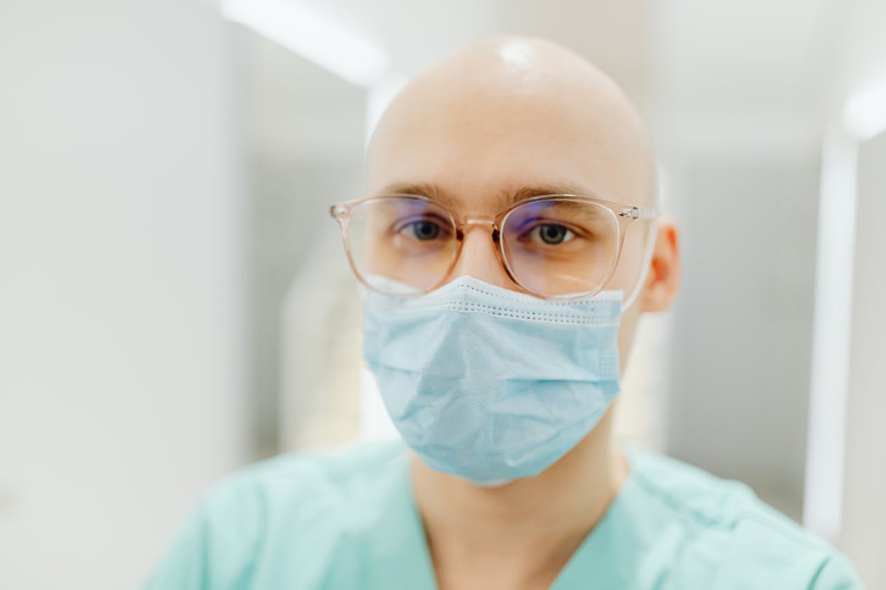 Close-up of a health worker wearing a surgical mask and glasses indoors.