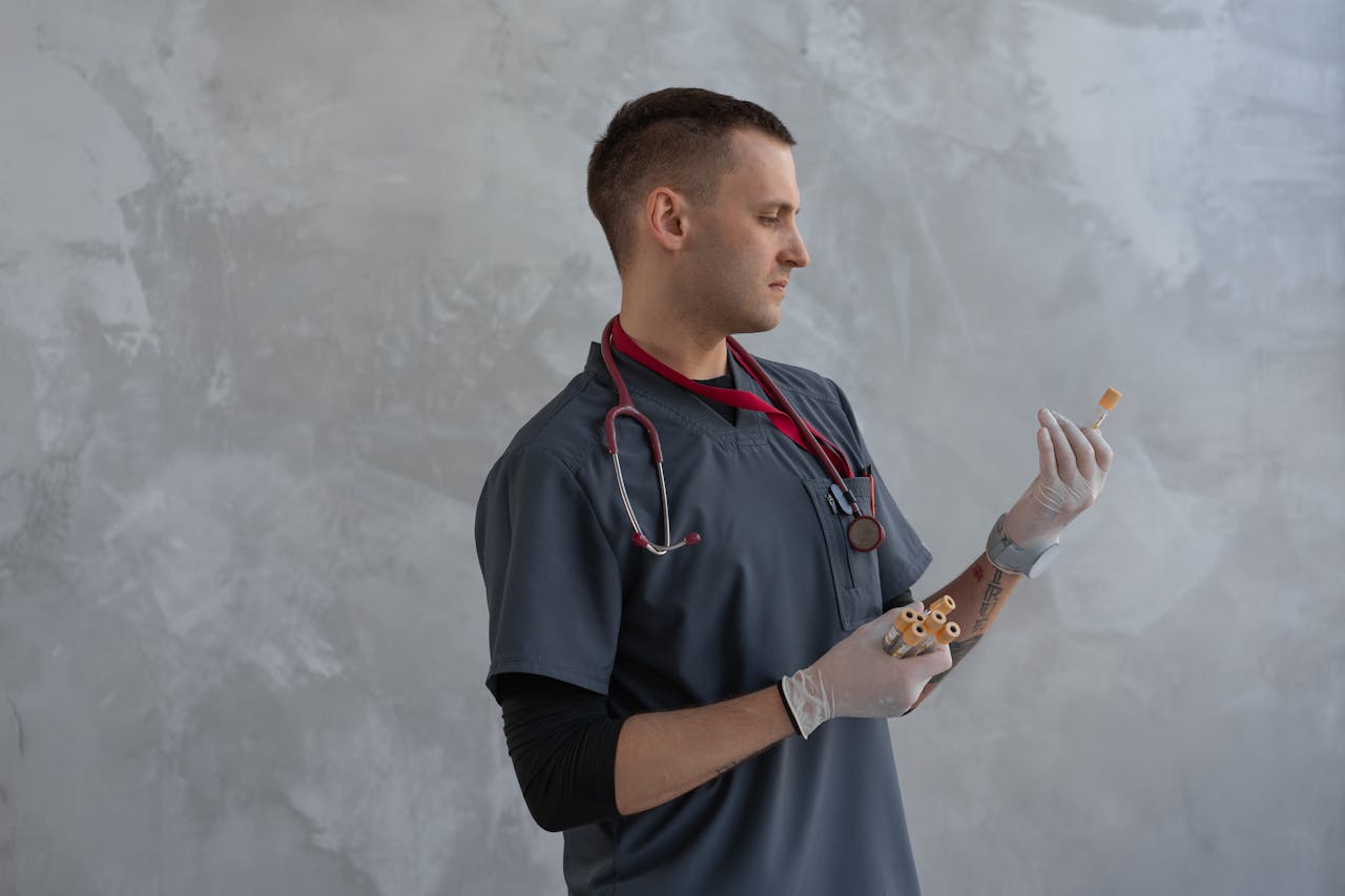 A male doctor in scrubs and gloves analyzing a specimen with focus indoors.